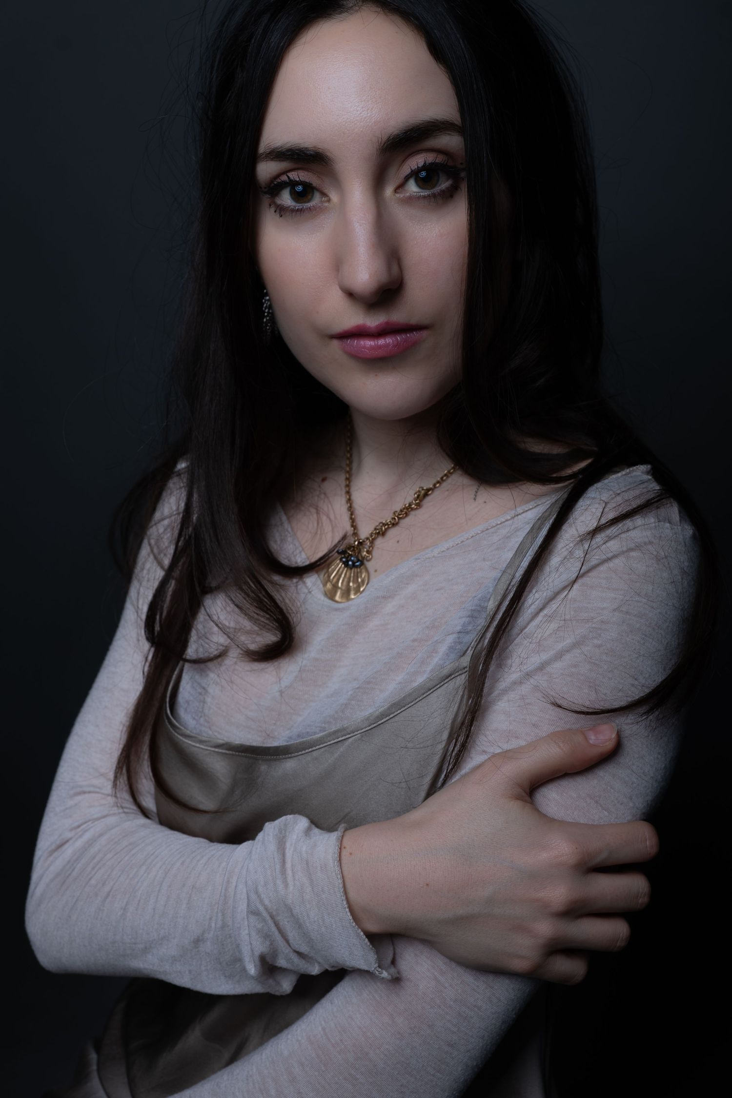 Dramatic portrait in dark lighting with pendant necklace.