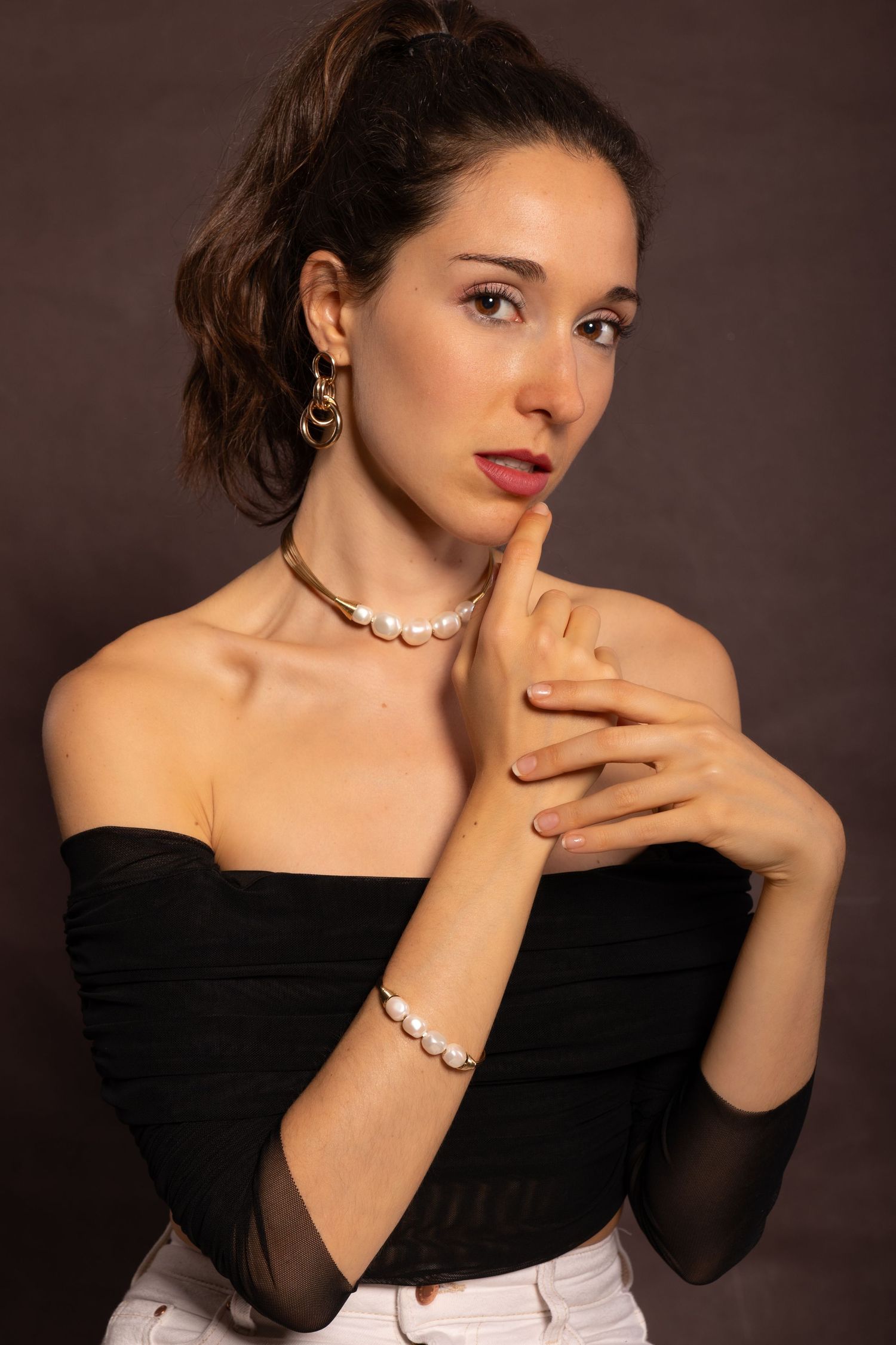 Elegant fashion portrait with pearl necklace and off-shoulder black top.