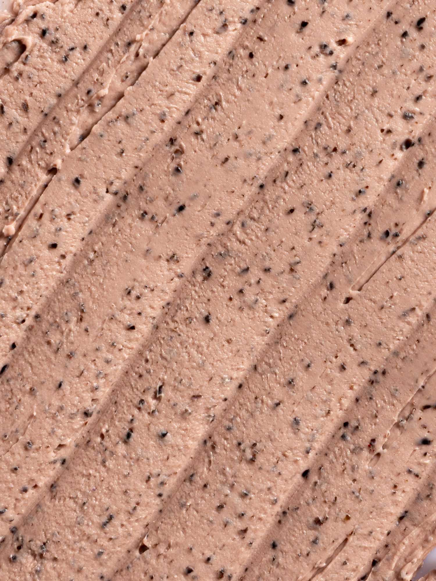 Close-up texture of rough brown concrete or stone surface with diagonal grooves and small embedded pebbles.