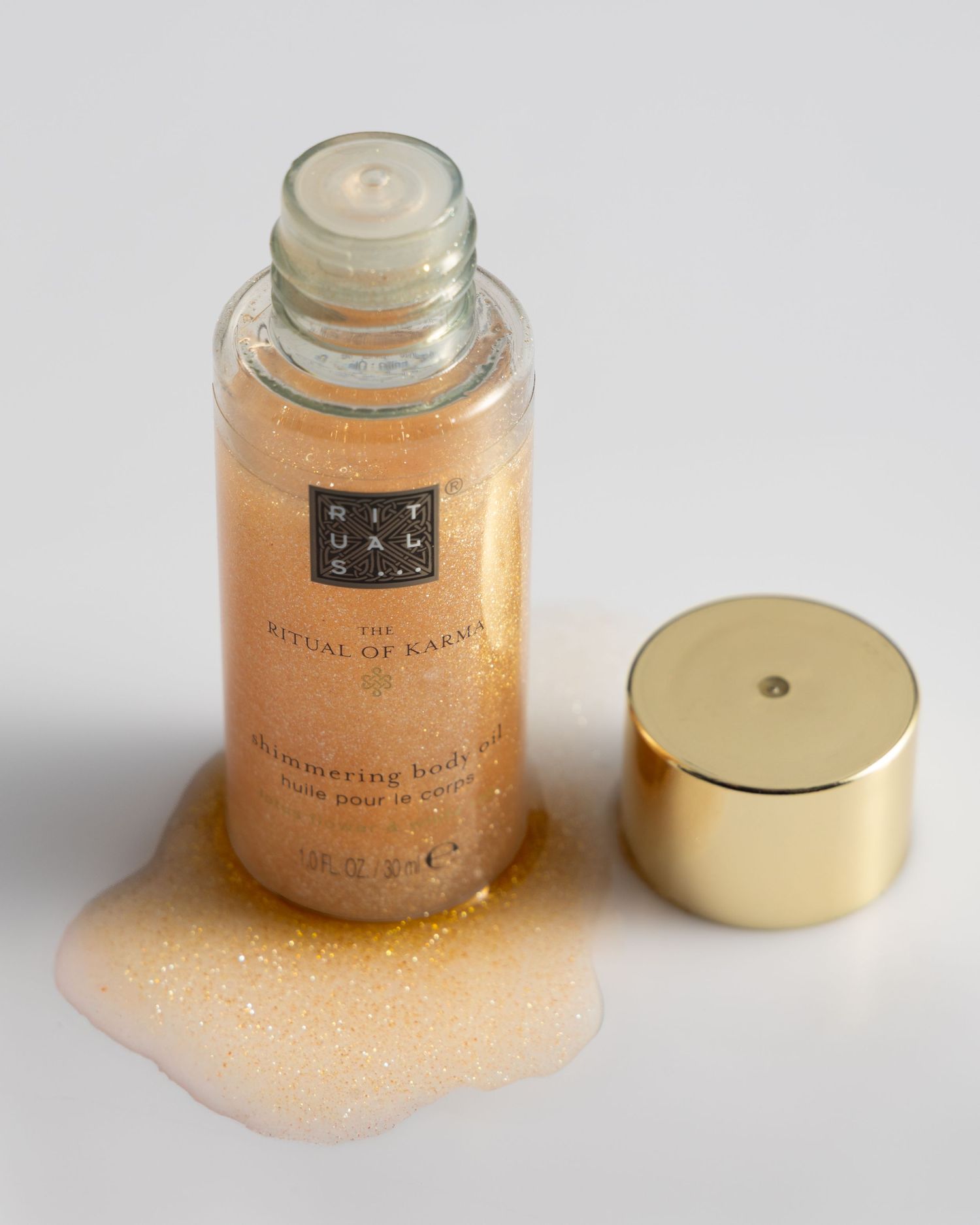 A gold-lidded jar of shimmering peach-colored cosmetic powder spills onto a white surface in multiple views.