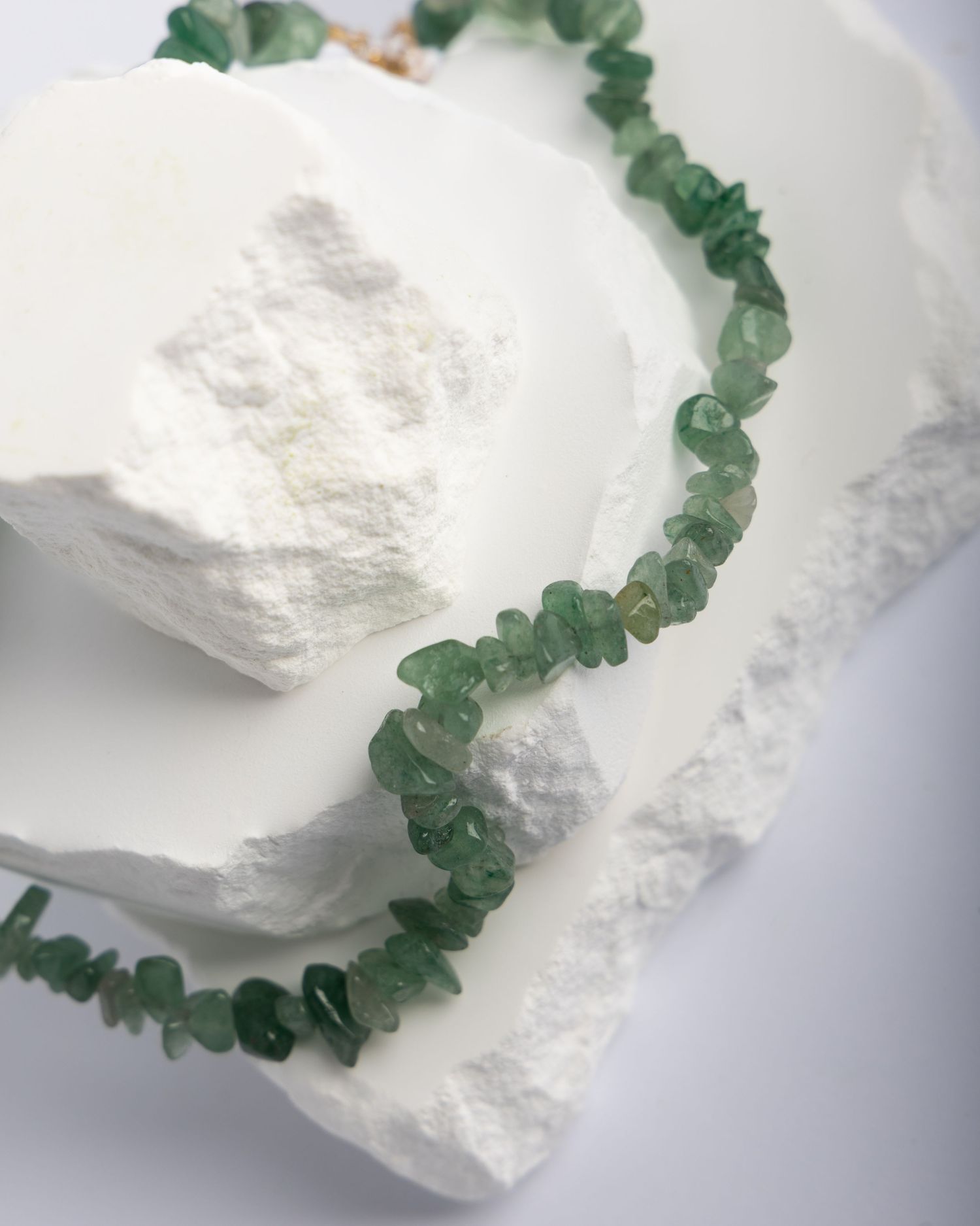 Green crystal beads on a white quartz crystal display a natural contrast in mineral jewelry design.