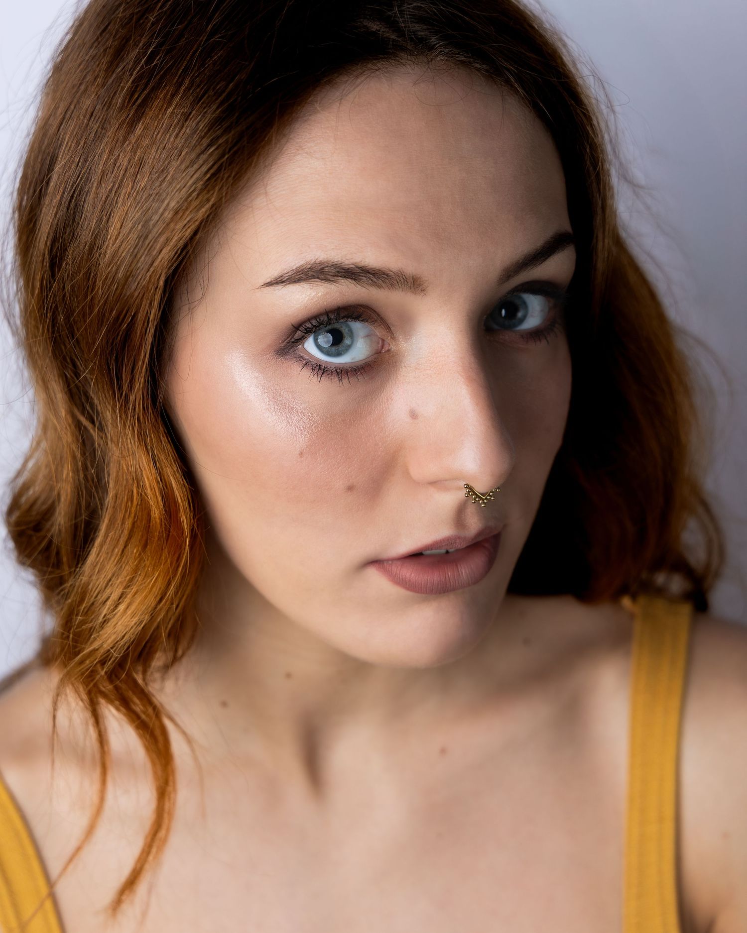 Portrait photograph of someone with brown hair and a yellow top against a light background.