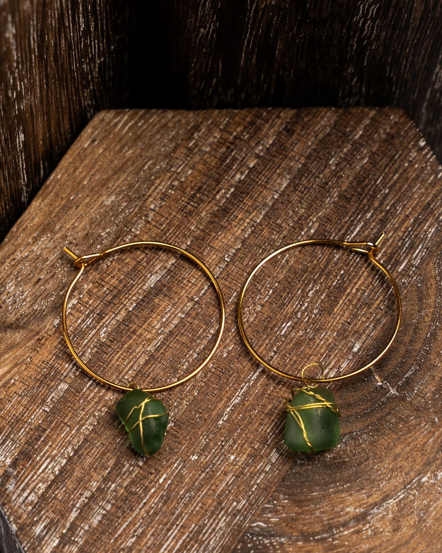 Eight stages showing the process of making minimalist green stone hoop earrings on a rustic wooden surface.