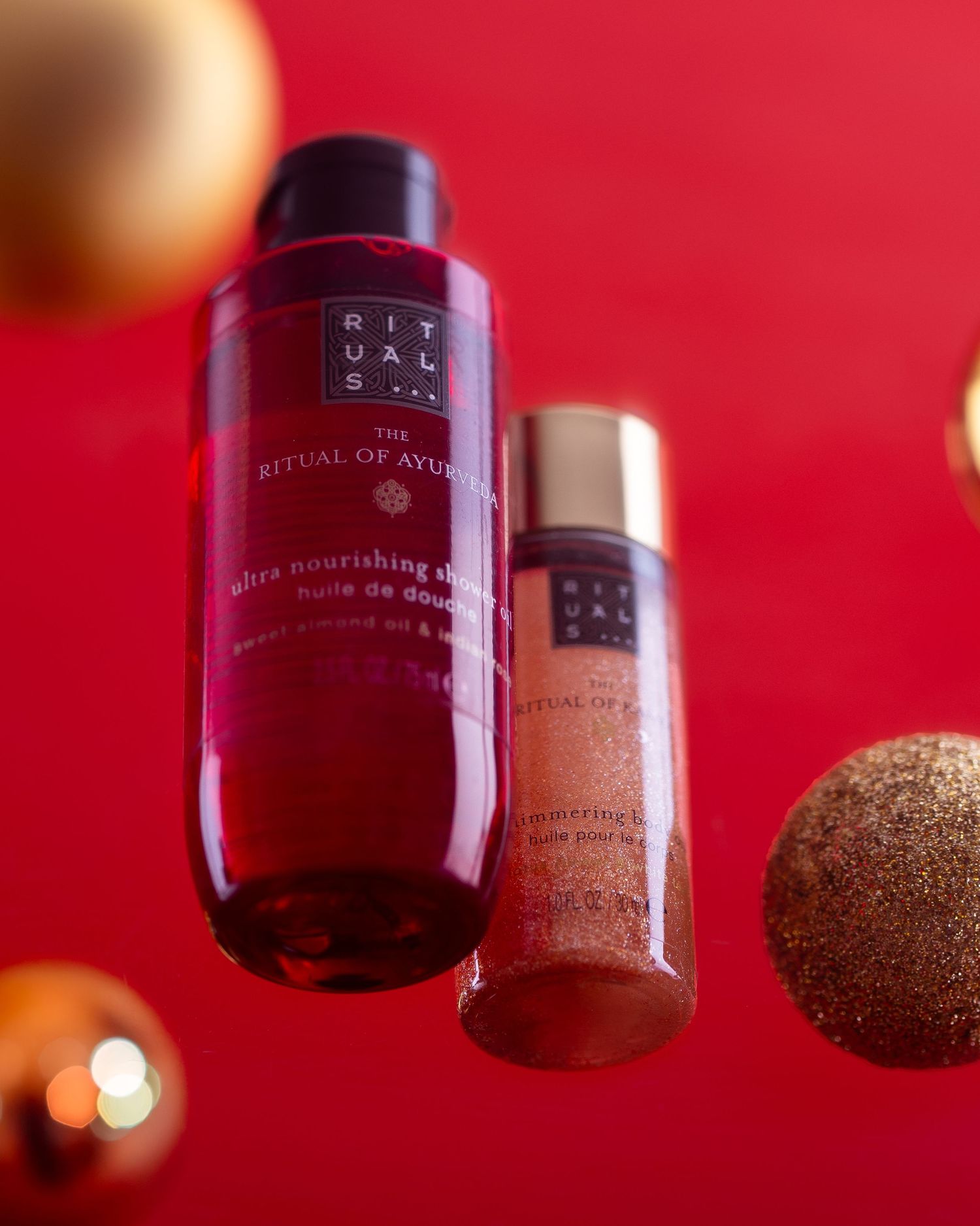Rituals beauty products floating against a vibrant red background with golden Christmas ornaments.