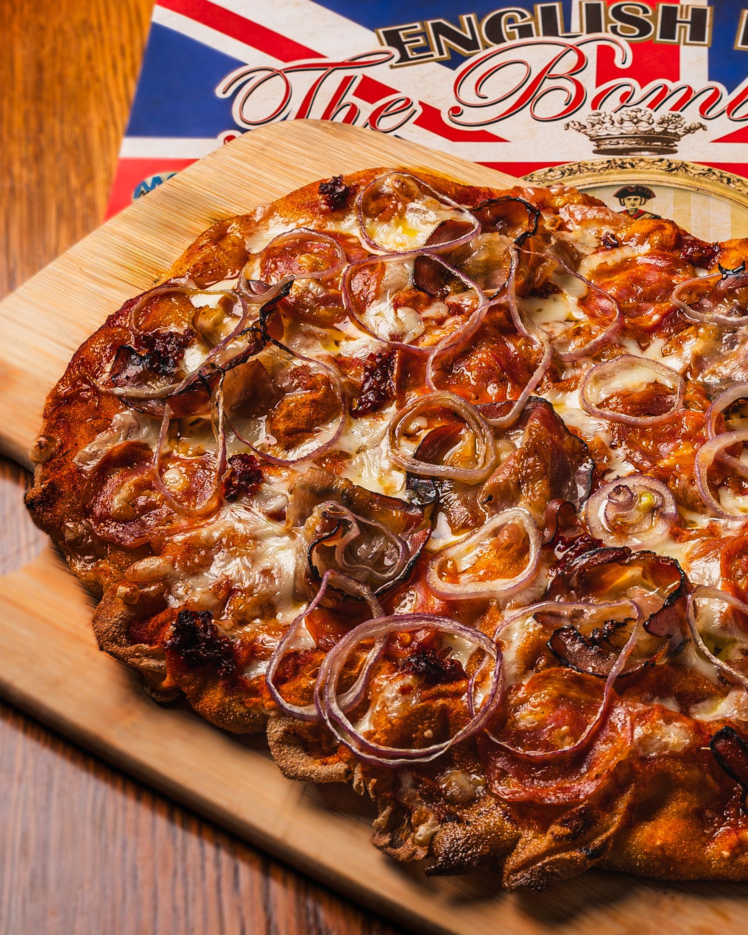 Grilled chicken on a wooden cutting board with caramelized onions, melted cheese and a British flag in the background.