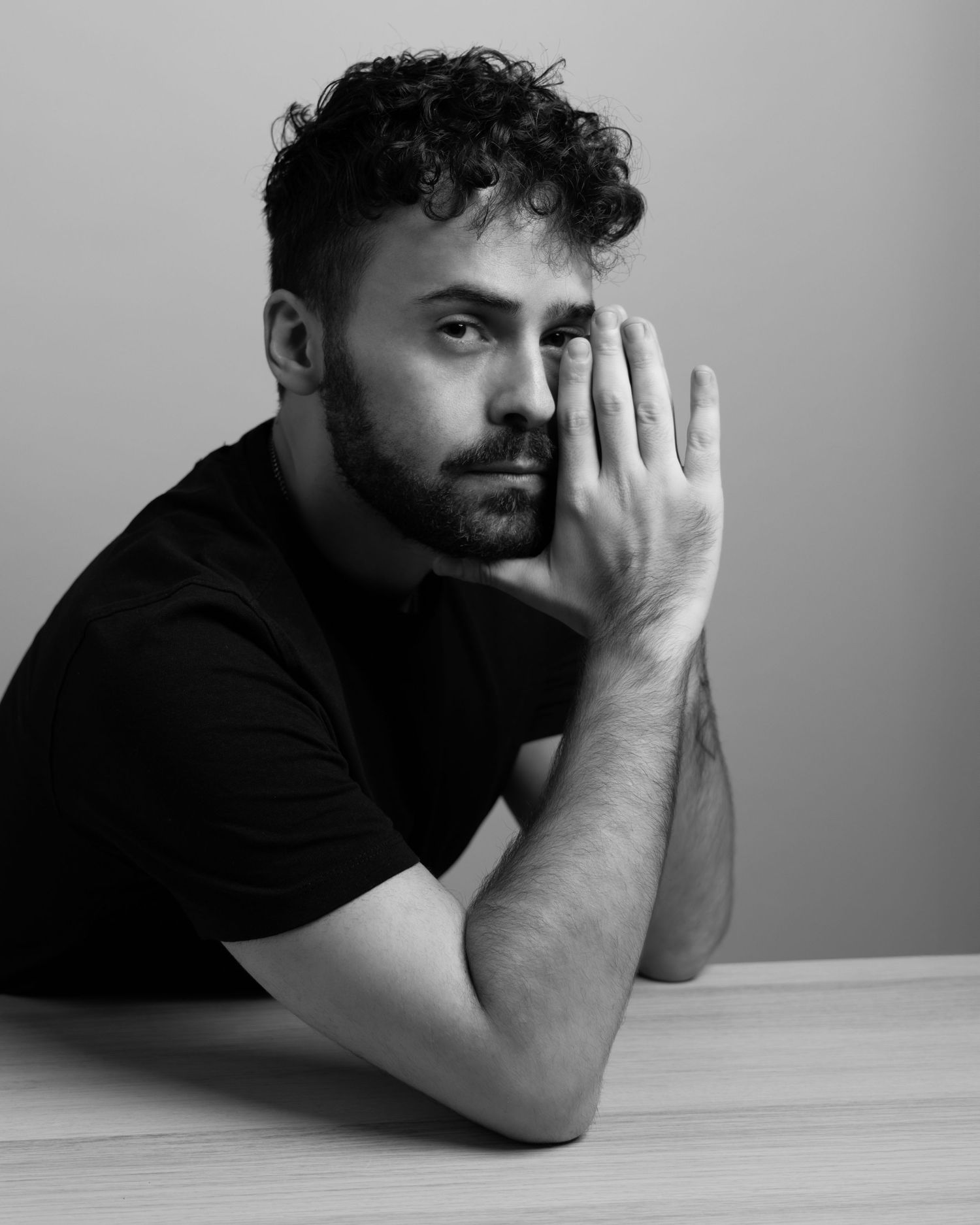 A series of black and white photos showing someone lying on their side against a light background in contemplative poses.