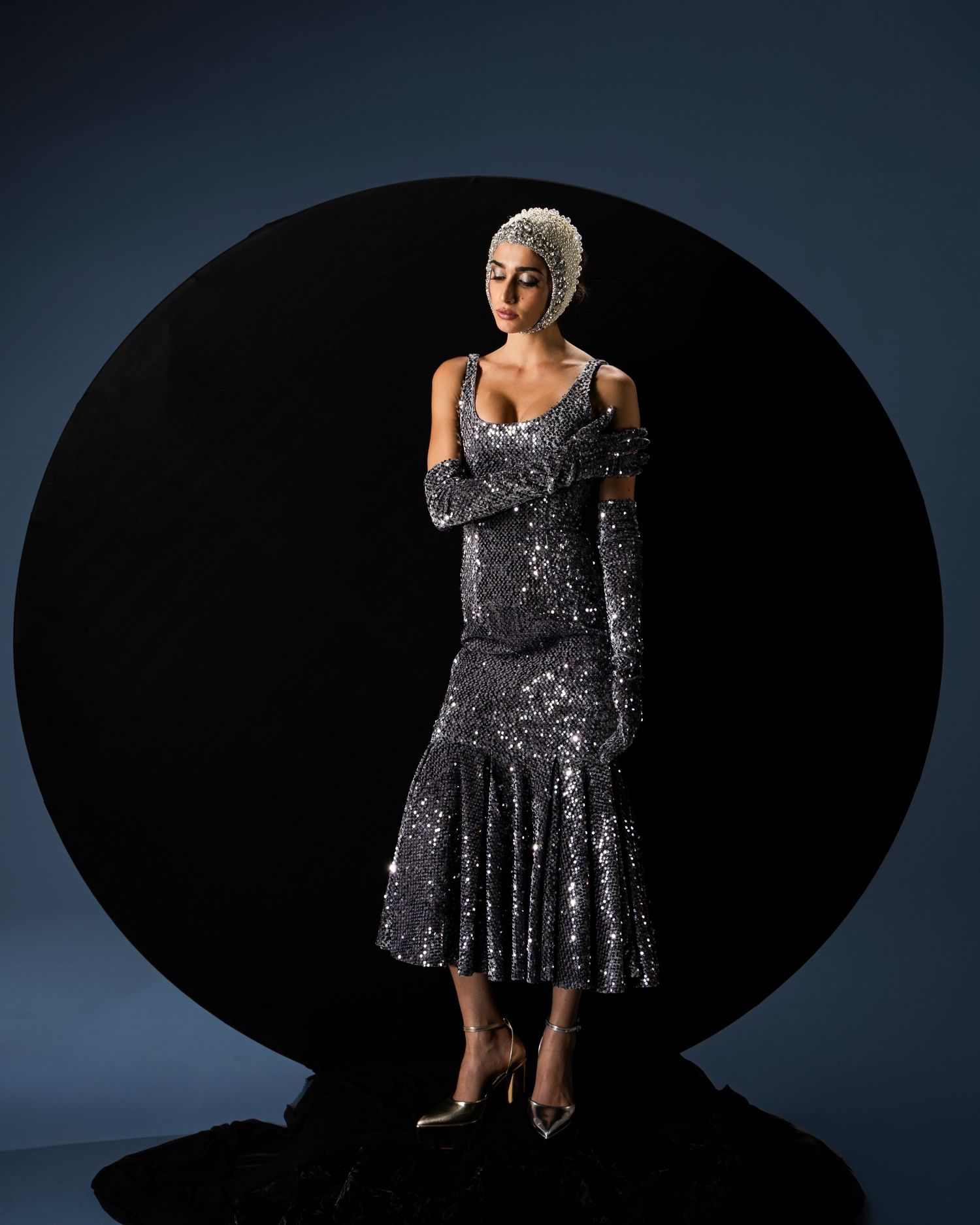 A sparkling silver sequin dress photographed in dramatic lighting against a dark background from multiple angles.