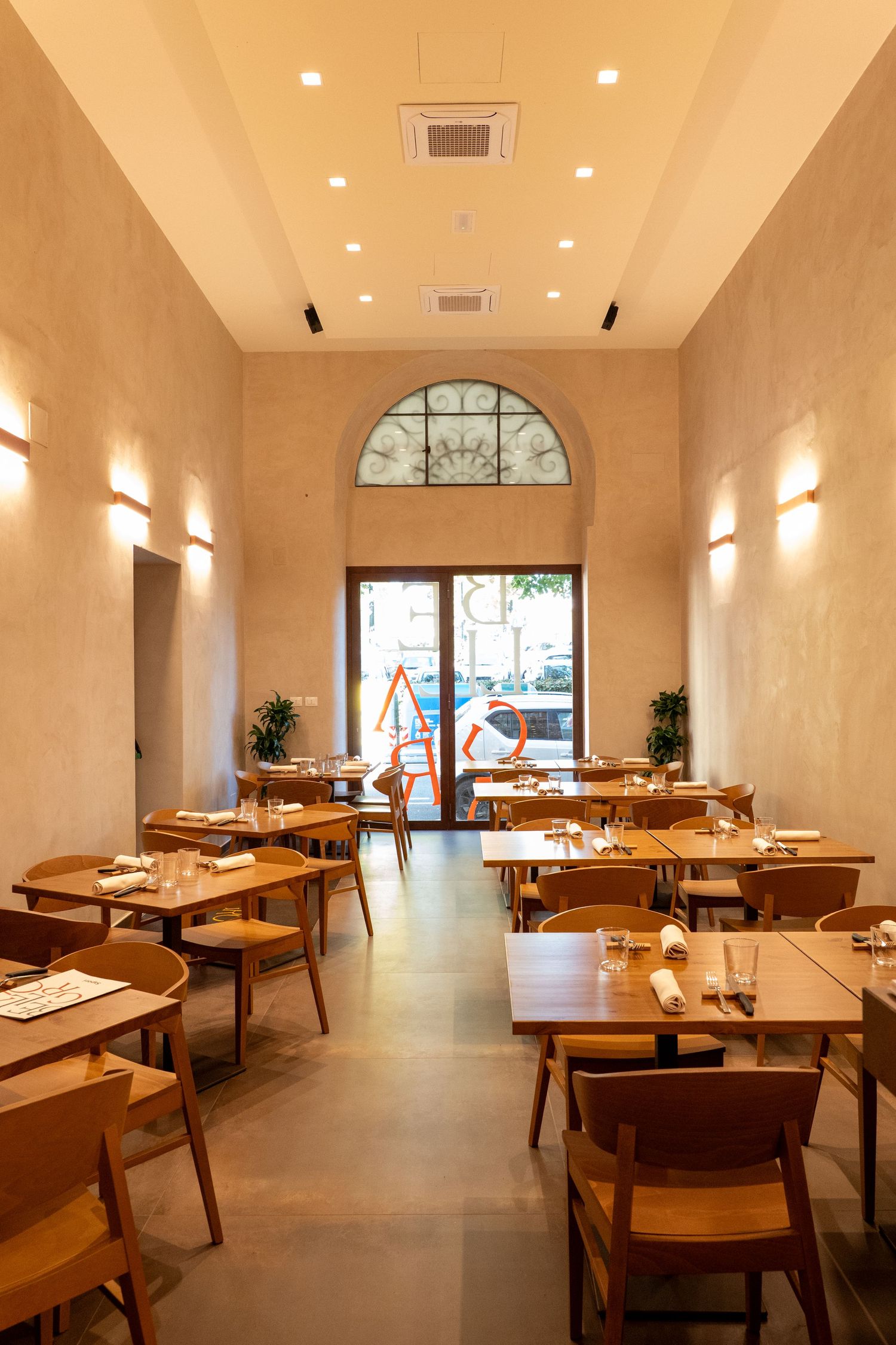 Modern upscale restaurant interior with wooden tables and warm lighting showcases elegant minimalist design and arched windows.