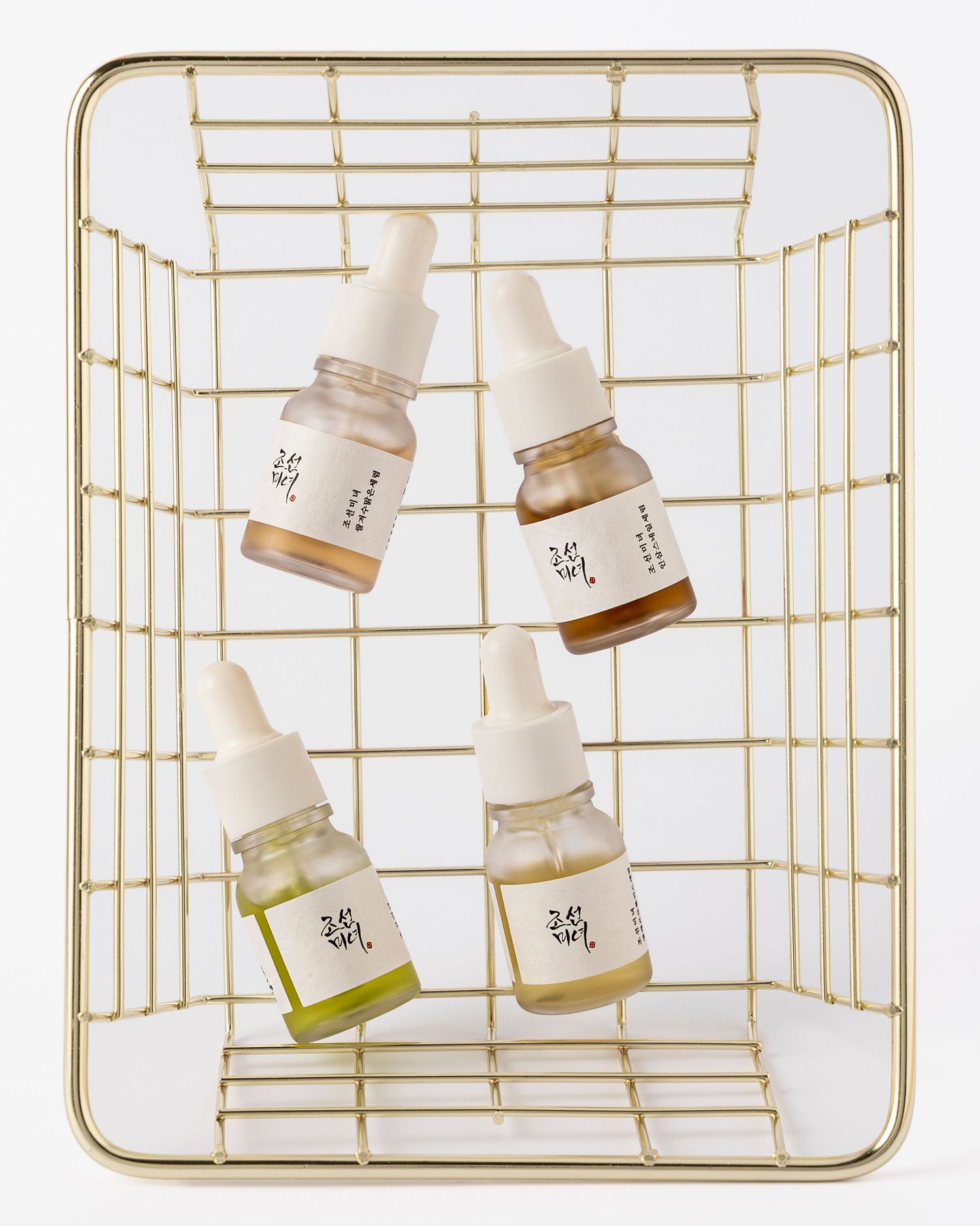 White ceramic jars with minimalist labels arranged on gold wire racks in a modern product display setting.