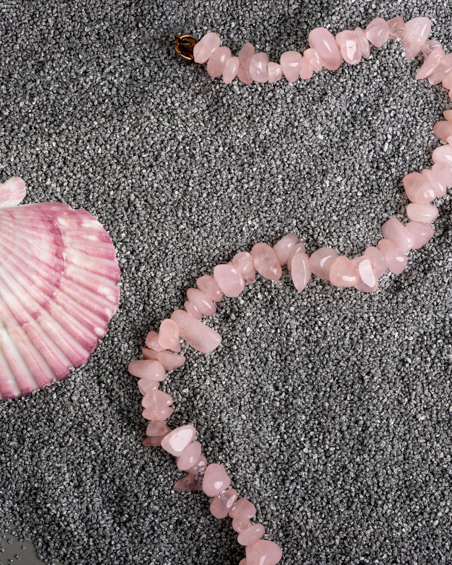 Pink cherry blossom petals arranged in a delicate spiral pattern against a textured grey background.