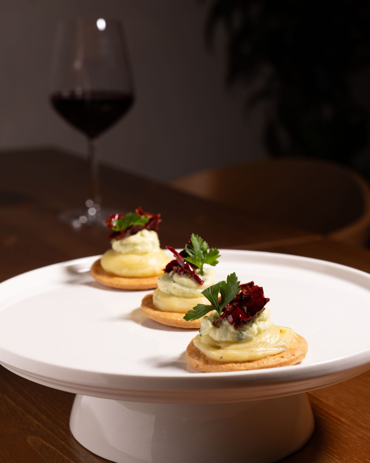 Elegant canapes with mousse and microgreens served on crispy butter crackers on a white plate.