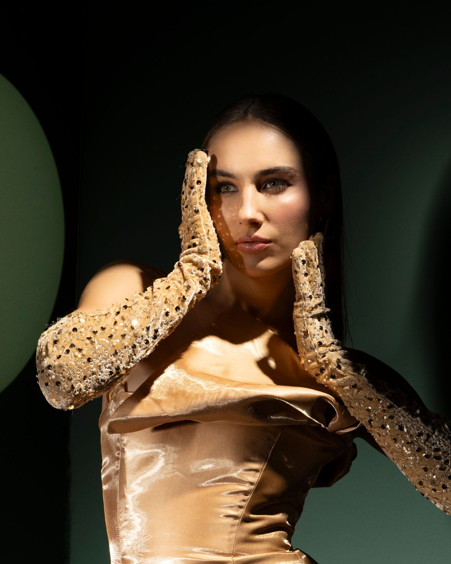 A dramatic fashion photo series showing a model in a champagne-colored silk dress against a dark background.
