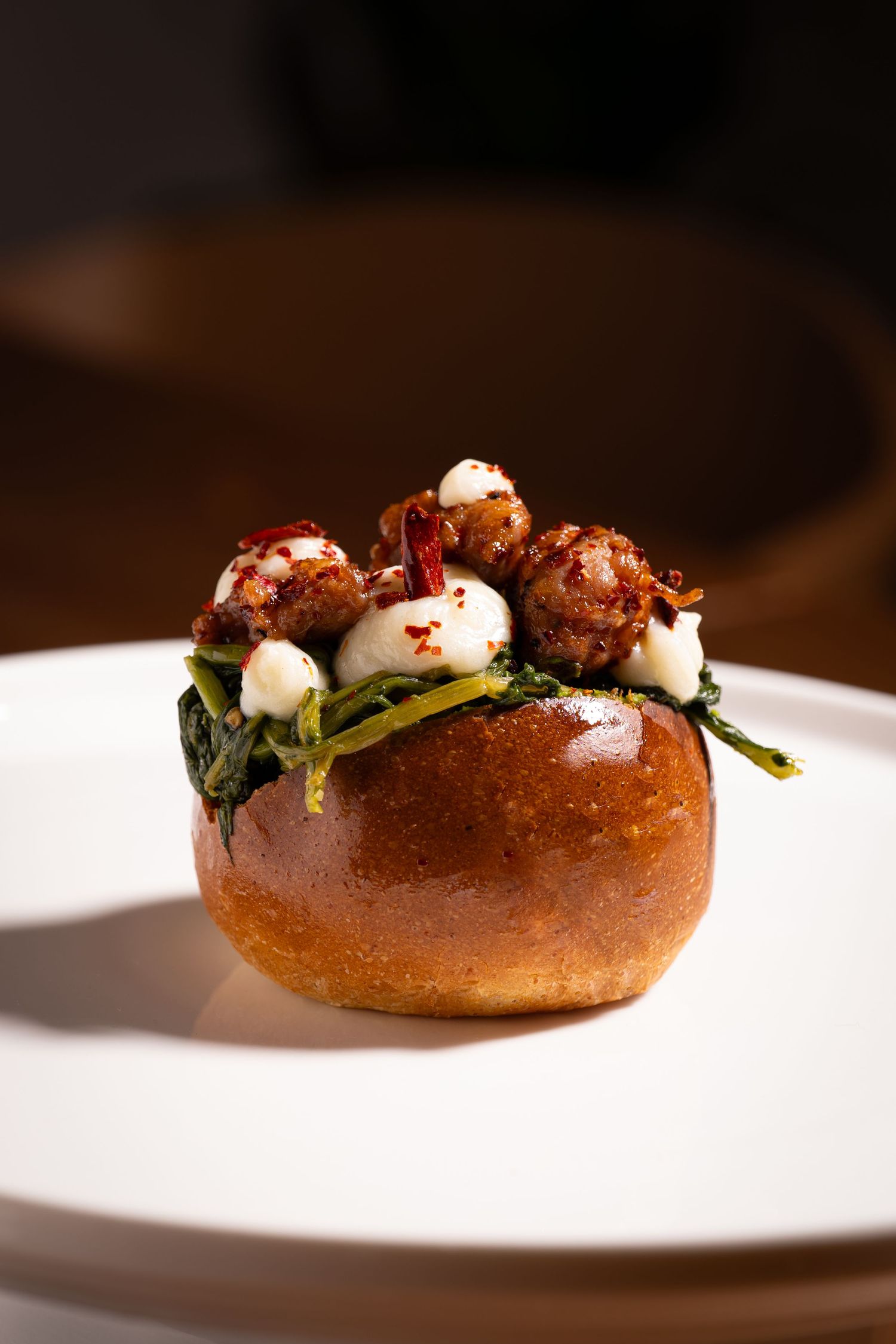 A sequence of photos showing a gourmet bagel with fresh toppings artfully presented on a white plate against dark background.