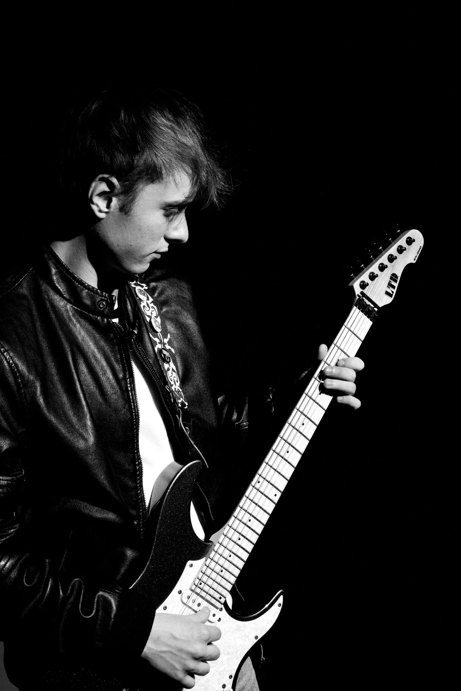 Moody black and white portrait of guitarist playing electric guitar.