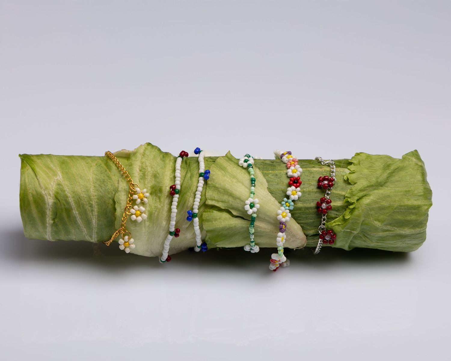 Green cabbage leaf rolled into a long tube with small decorative figures arranged on top against a light background.