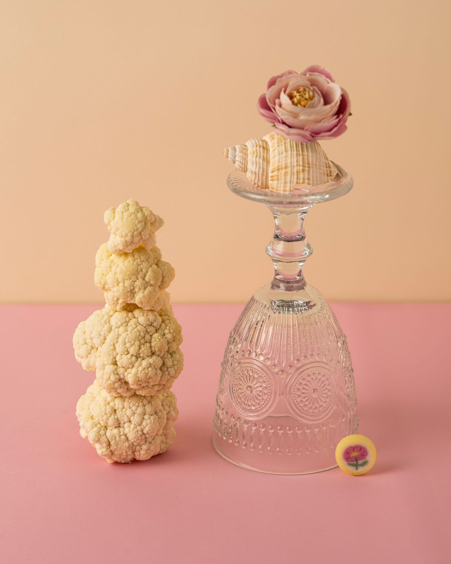 A teddy bear and vintage glass bowl arranged on a pink background in a minimalist composition.