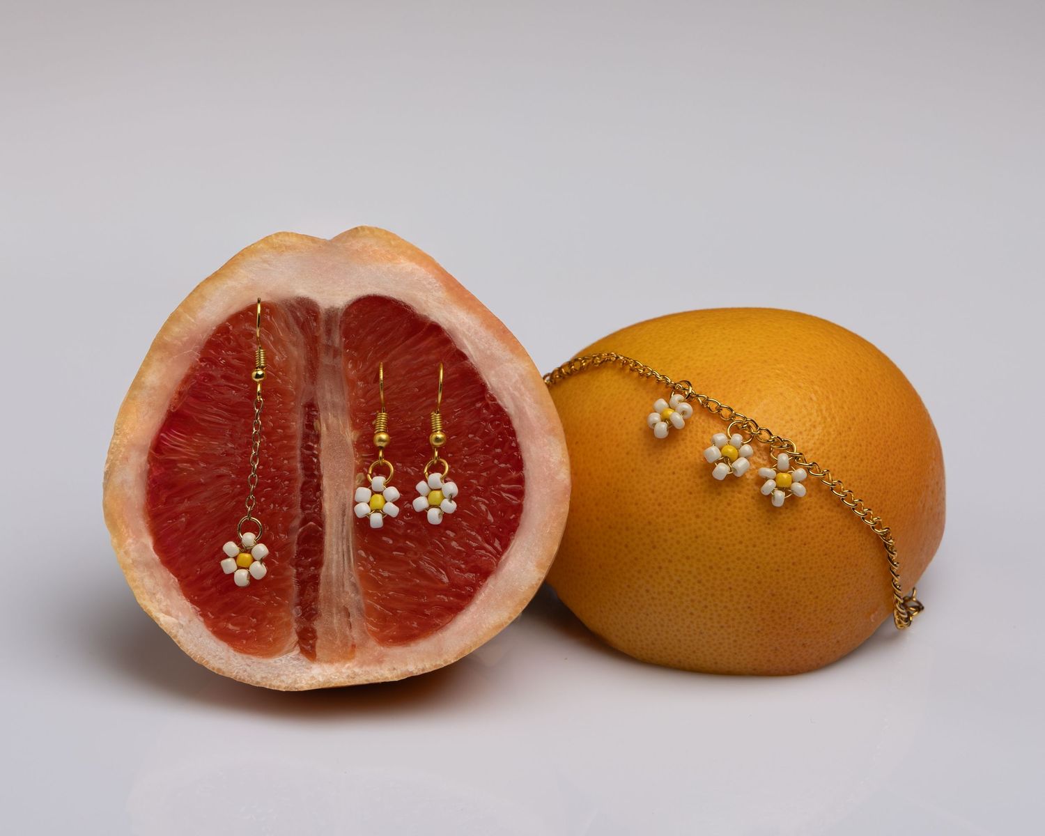 A sequence of five images showing a cut grapefruit and orange being progressively stitched together with thread.