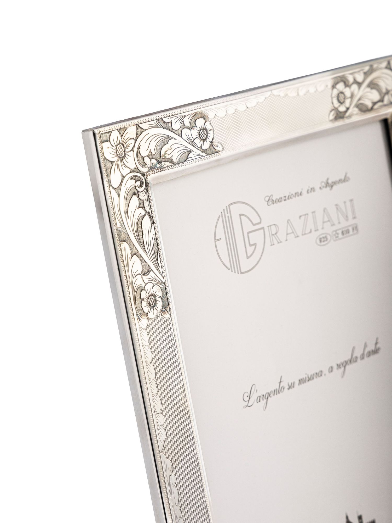 Close-up detail of decorative silver picture frame with intricate scrollwork pattern in corner.