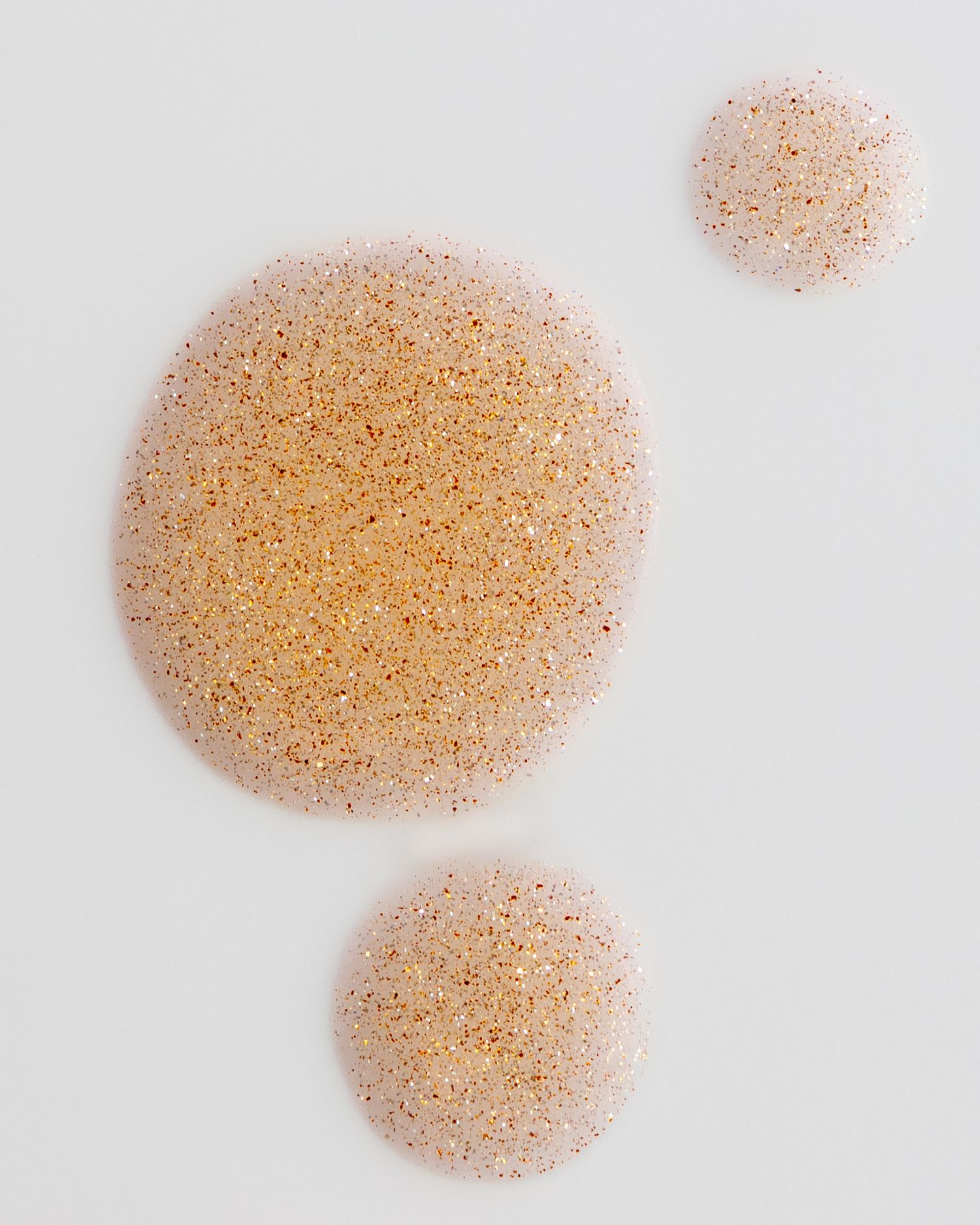 Two circular formations of pink and orange sugar crystals against a white background.