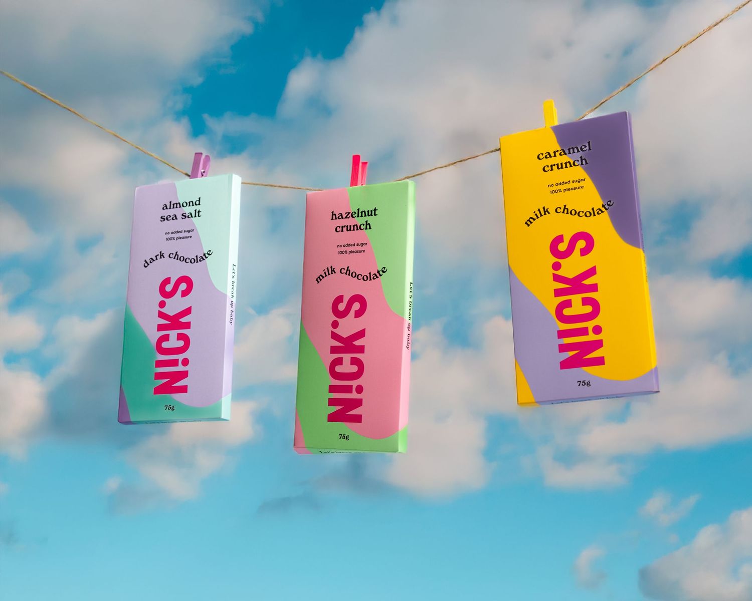 Colorful popcorn snack packages hanging on clothesline with pink clips against blue cloudy sky.