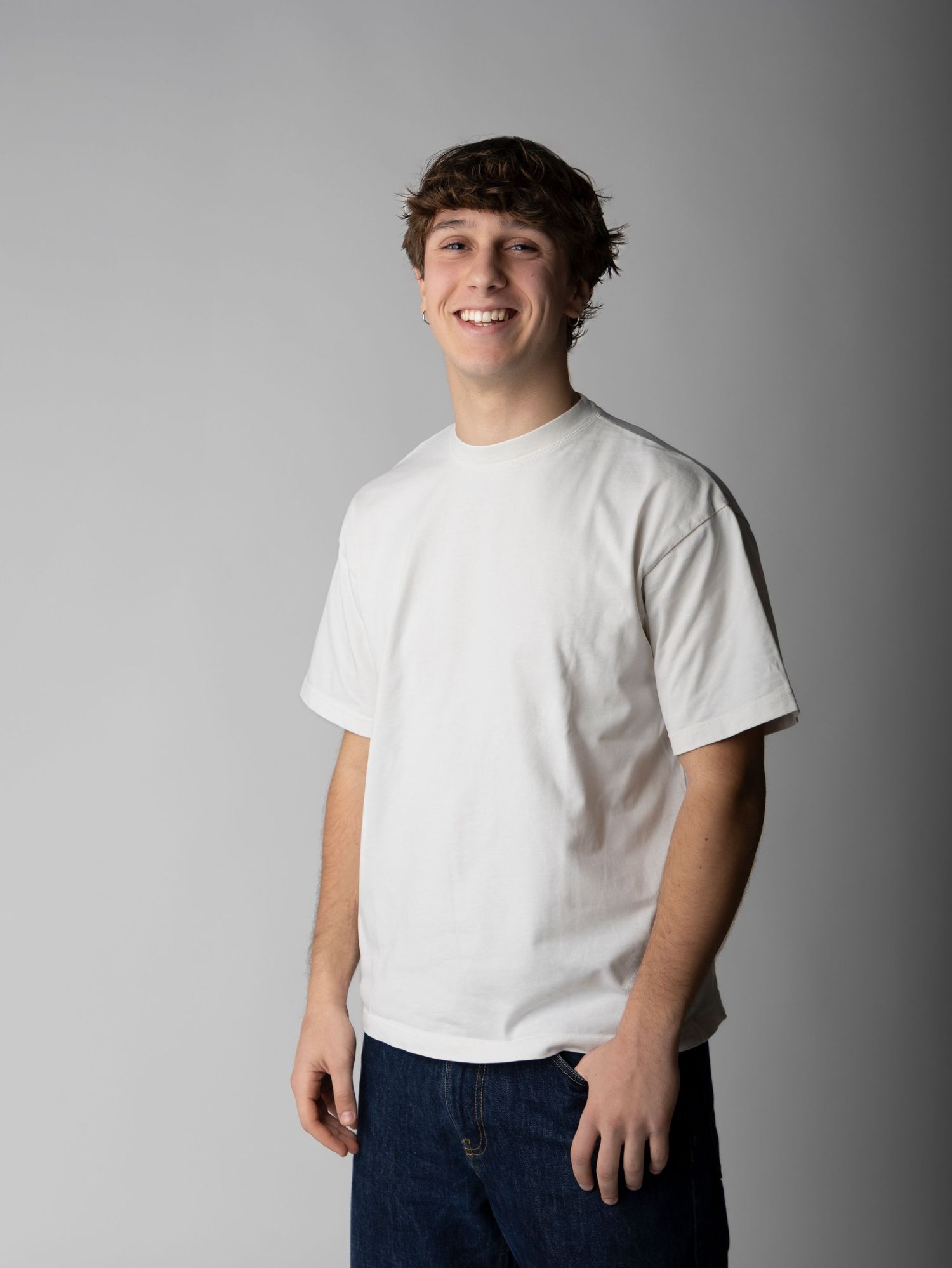 Person in a white t-shirt and jeans stands against a gray background in three similar poses.