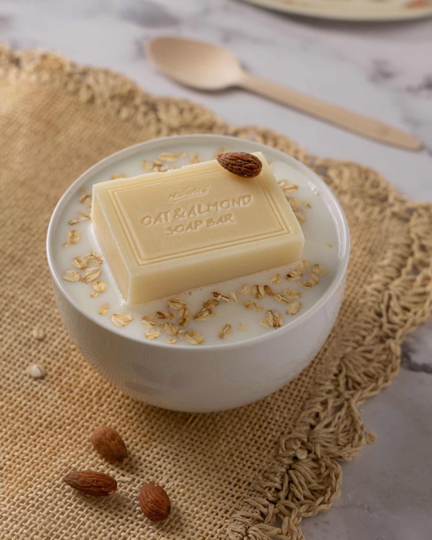 A close-up view of soap bars with almond pieces on a crocheted doily against a stone surface.