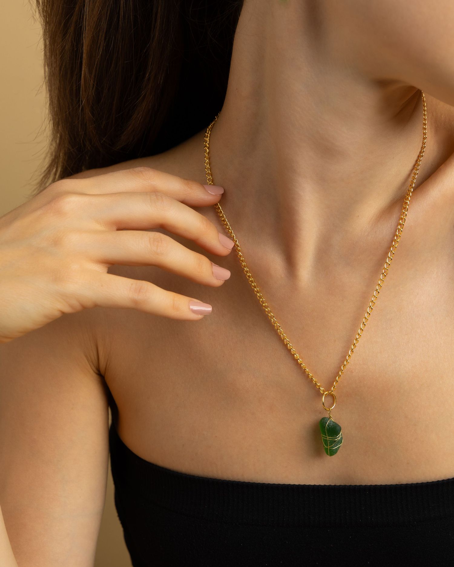 A gold chain necklace with emerald pendant shown in multiple views against a dark background.