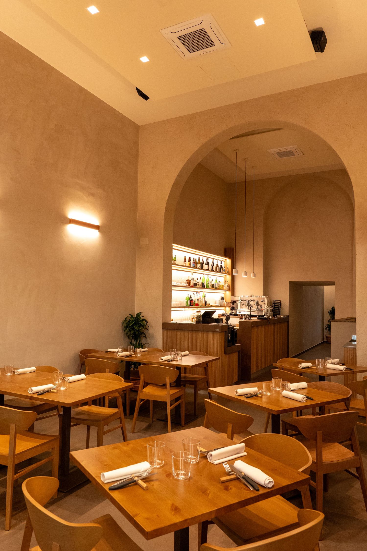 Warm lit restaurant interior with wooden tables and archways creating an intimate dining atmosphere.
