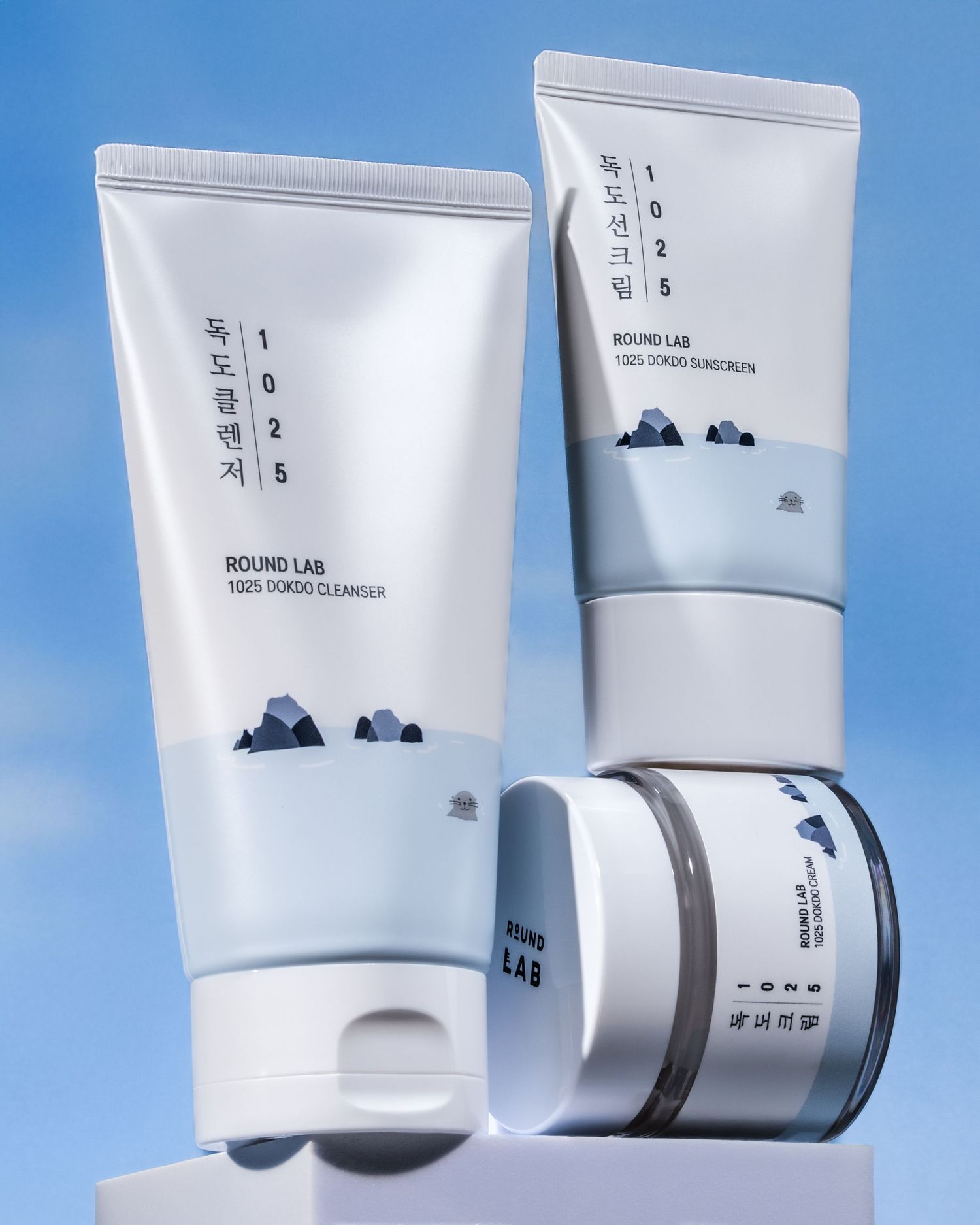 Minimalist white skincare product tubes and containers displayed on a blue background showcasing clean packaging design.