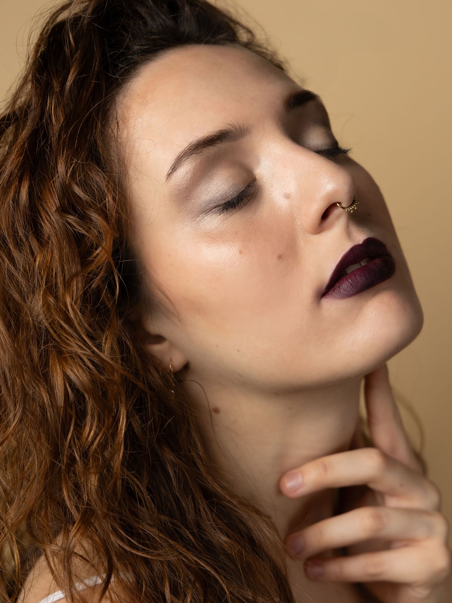 Artistic beauty portraits showcase a model with closed eyes against a neutral beige backdrop.