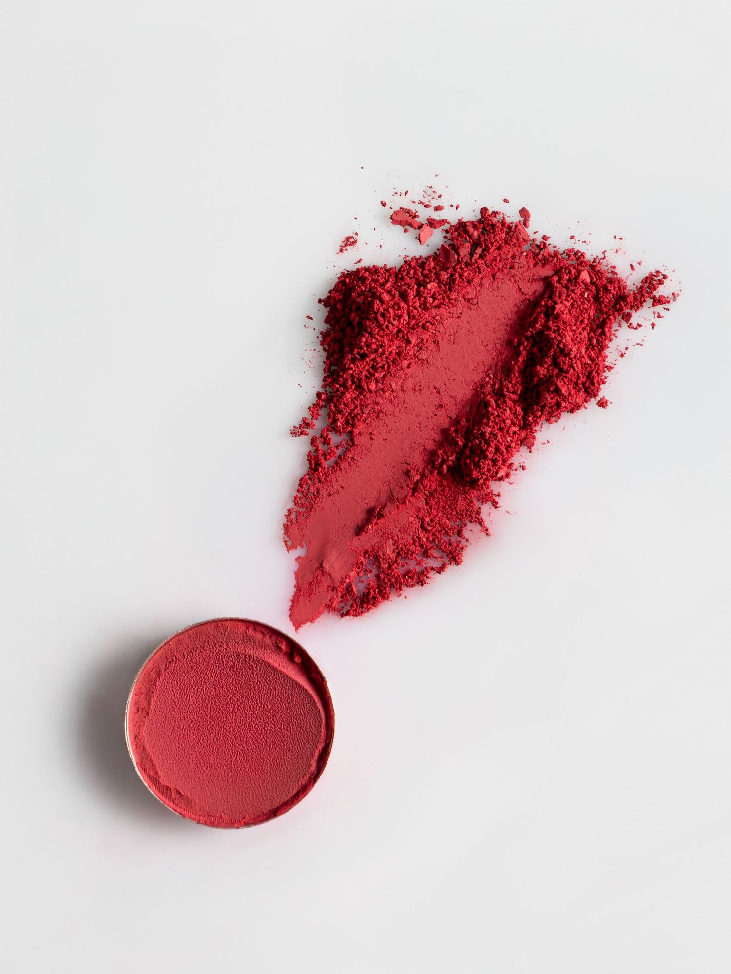 Broken red makeup powder gradually disperses across three frames on a white background.