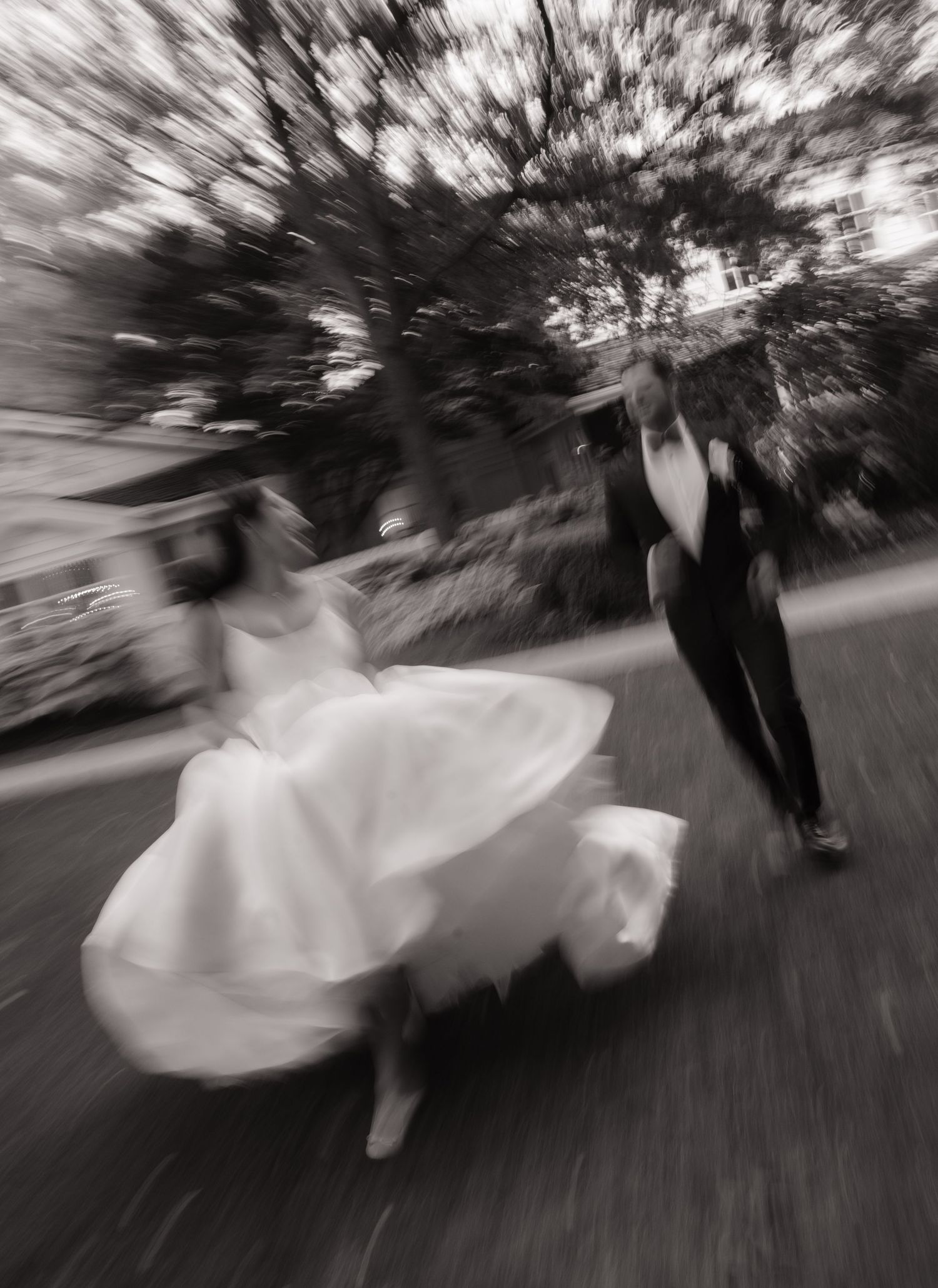 Black and white motion blur photo of a bride and groom joyfully running together on their wedding day.