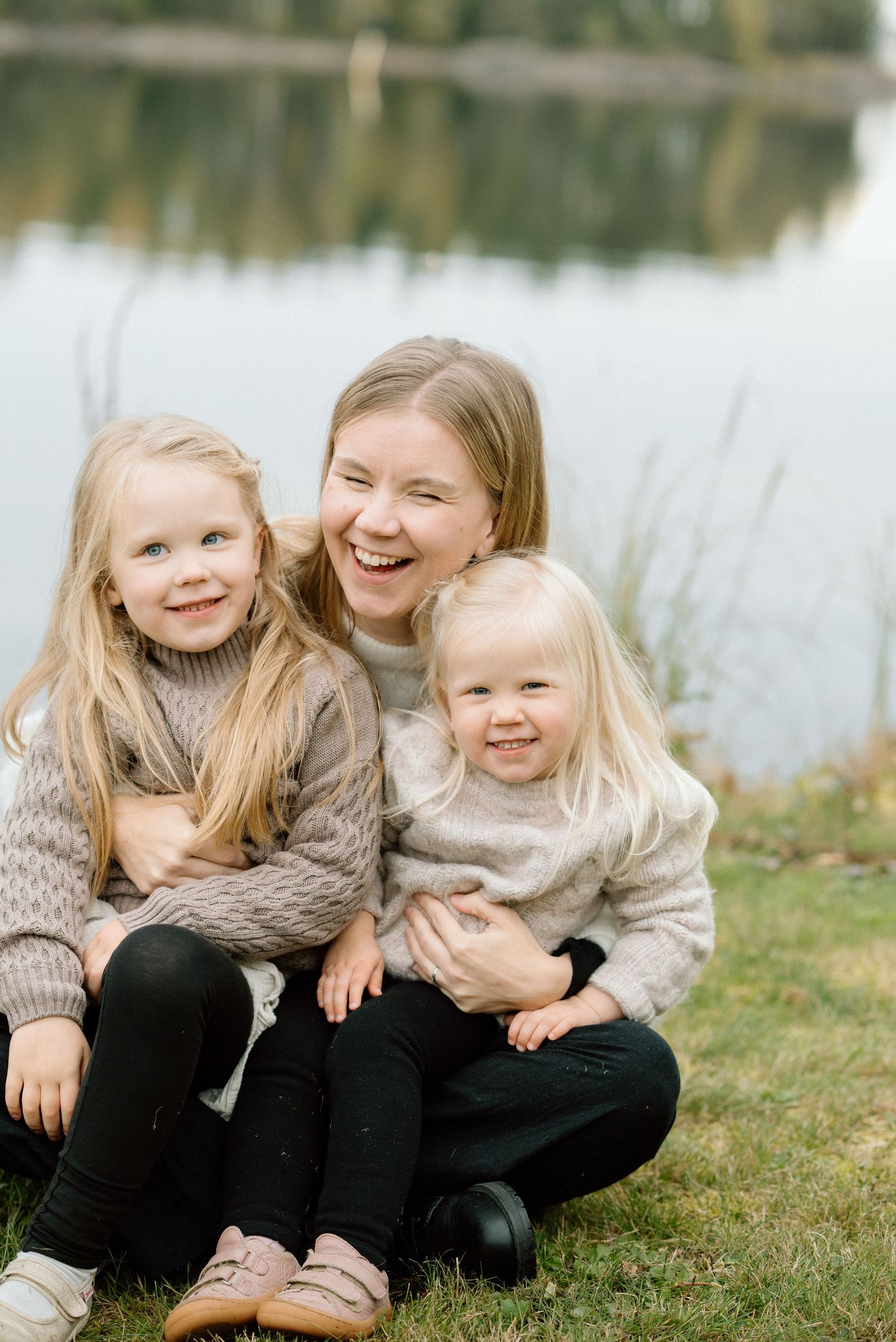 Äiti ja kaksi lasta rannalla sylikkäin nauramassa