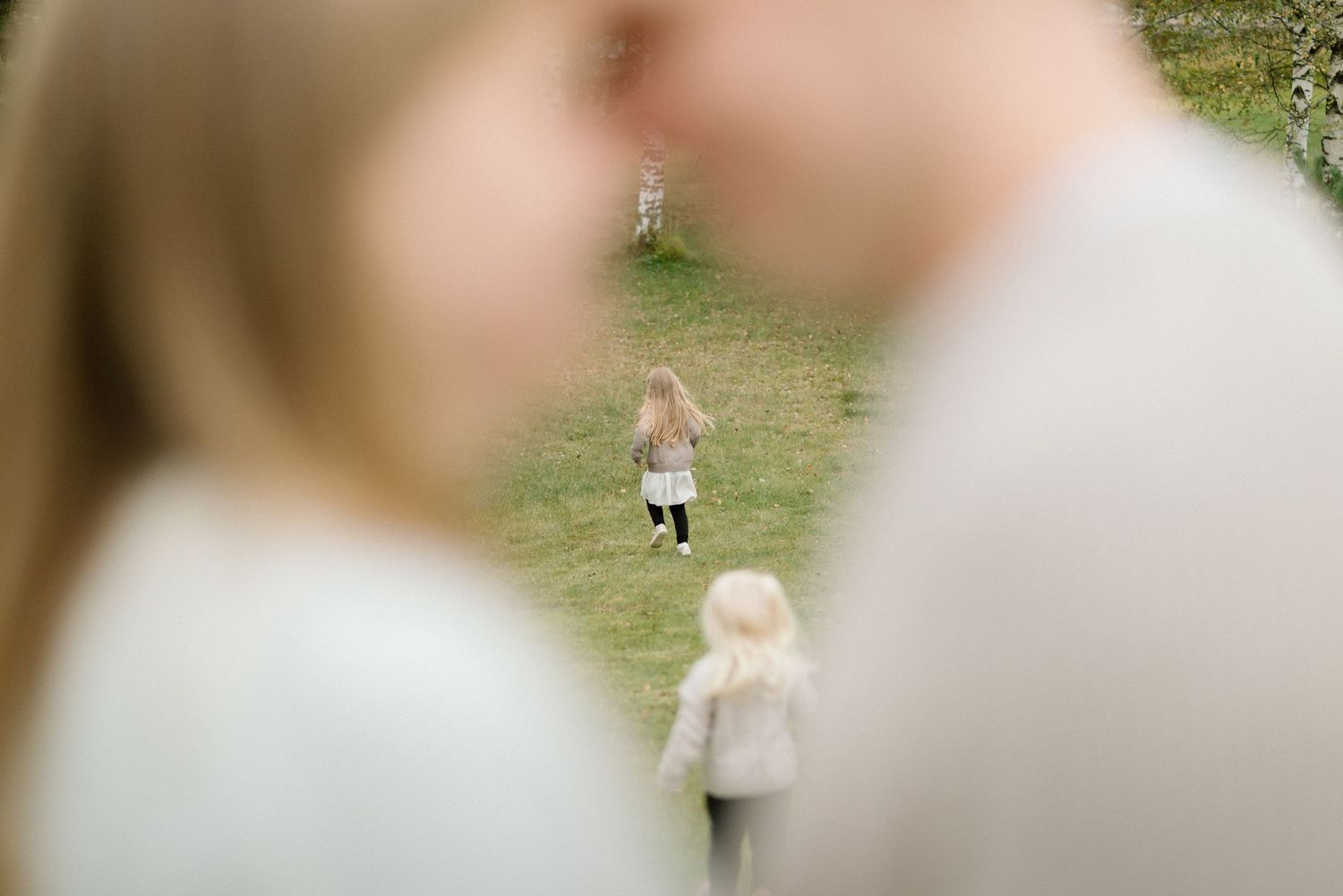 Lapset juoksevat poispäin kun vanhemmat halaavat toisiaan etualalla