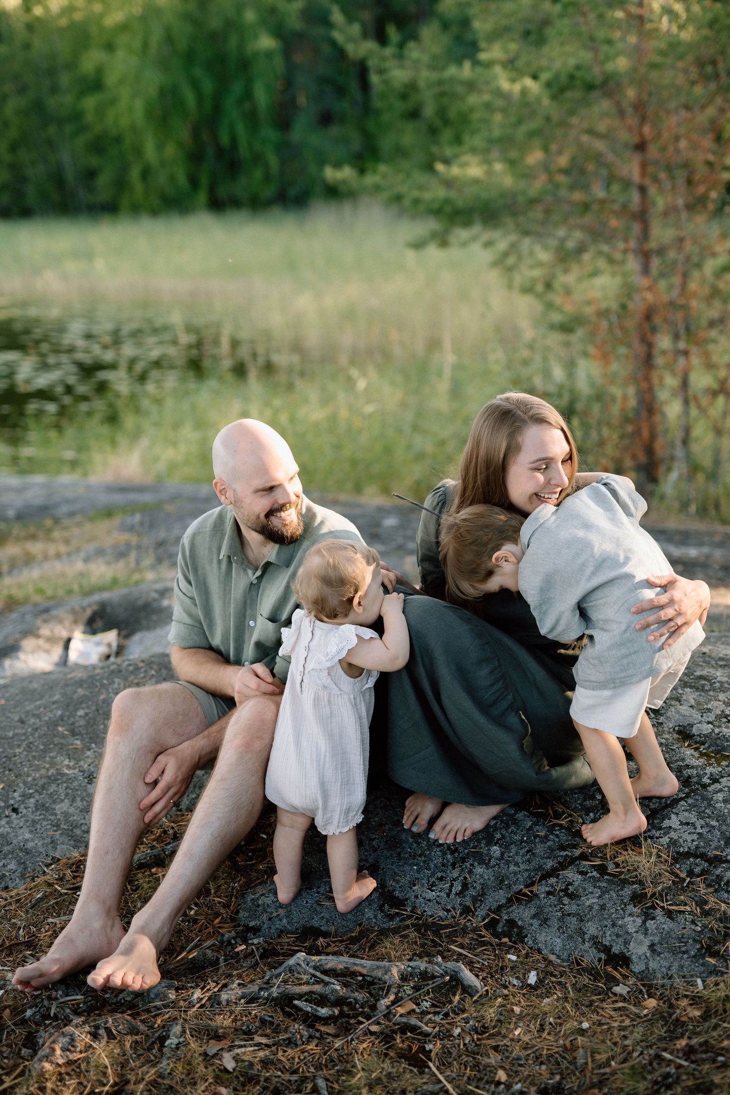 Perhe halailee toisianaan kalliolla rannalla
