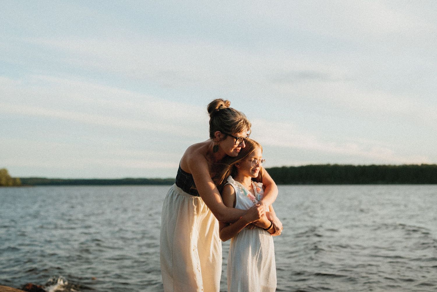 Äiti halaa kouluikäistä lastaan Saimaan rannalla