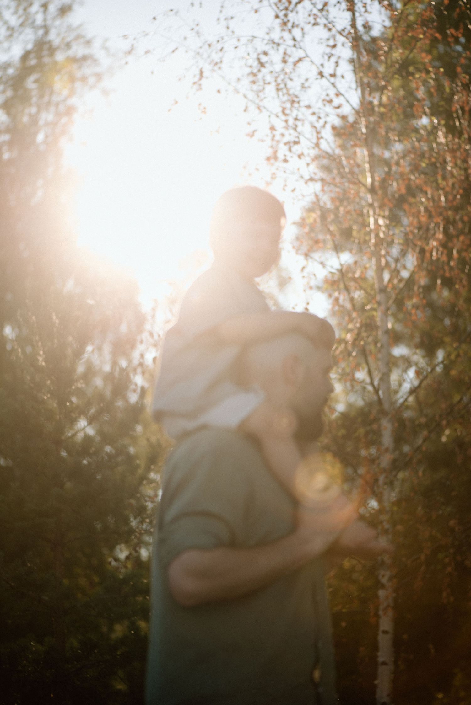Golden hour ja isä kantaa lasta reppuselässä - perhekuvaajan kuvaama tilanne