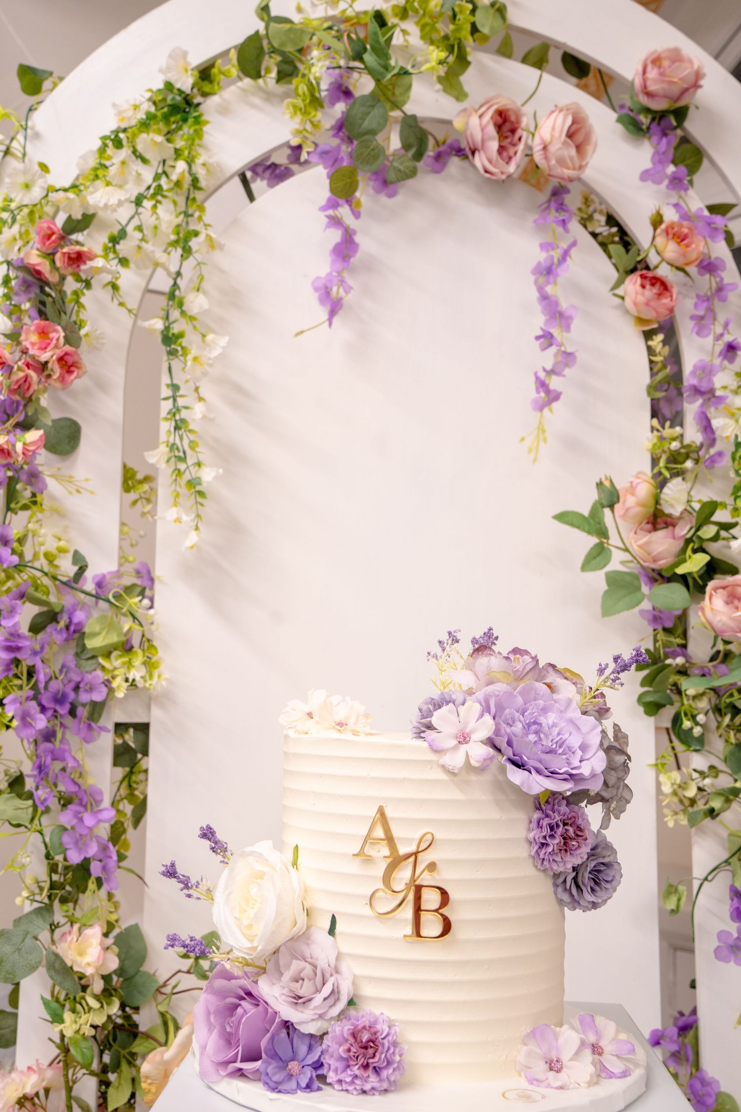 custom white cake with purple flowers and floral backboard setup, Tied in Time Photography.