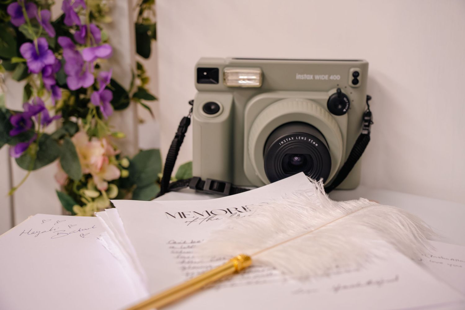 detail shot of camera, feather pen, purple flowers. Tied in Time Photography.