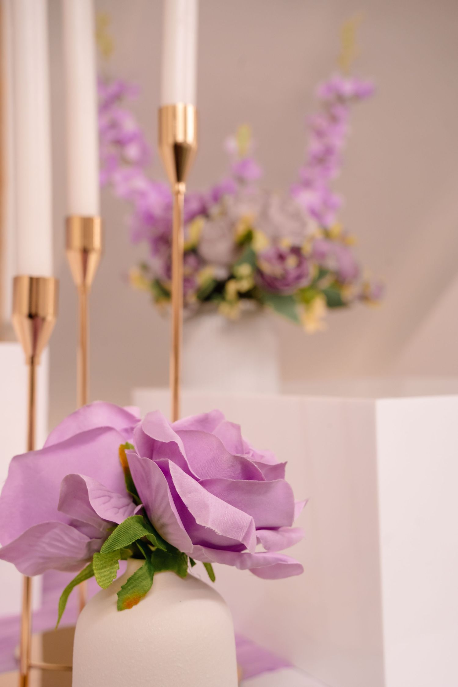 detail shot of purple flowers in white vases with candles in rose gold candle holders. Tied in Time Photography.