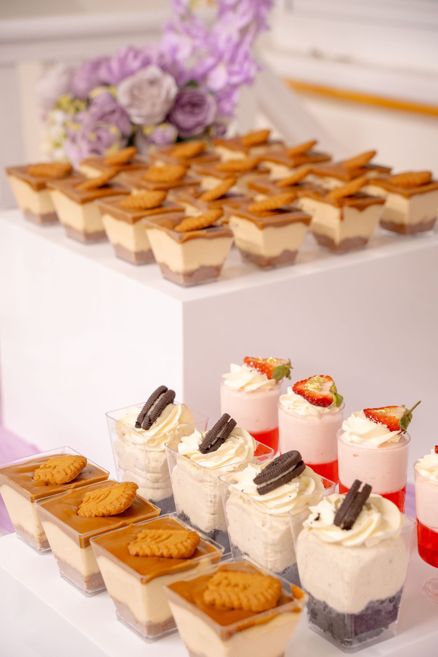 close up of deserts table with purple and white flower theme, Oreo cheesecake, strawberry trifle, biscoff cheesecake. Tied in Time Photos