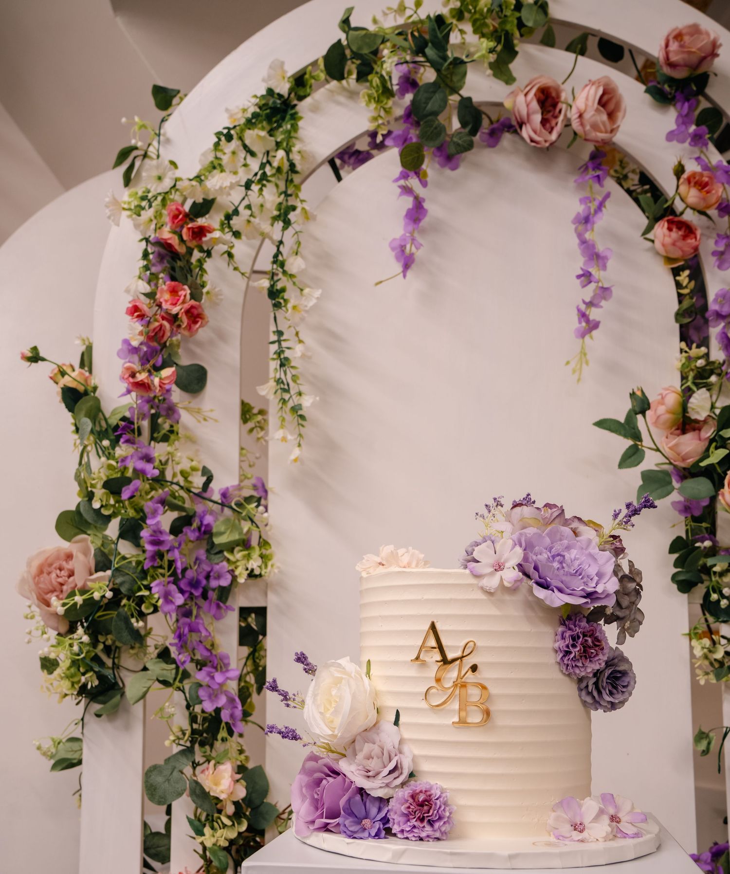 custom white cake with purple flowers and floral backboard setup, Tied in Time Photography.