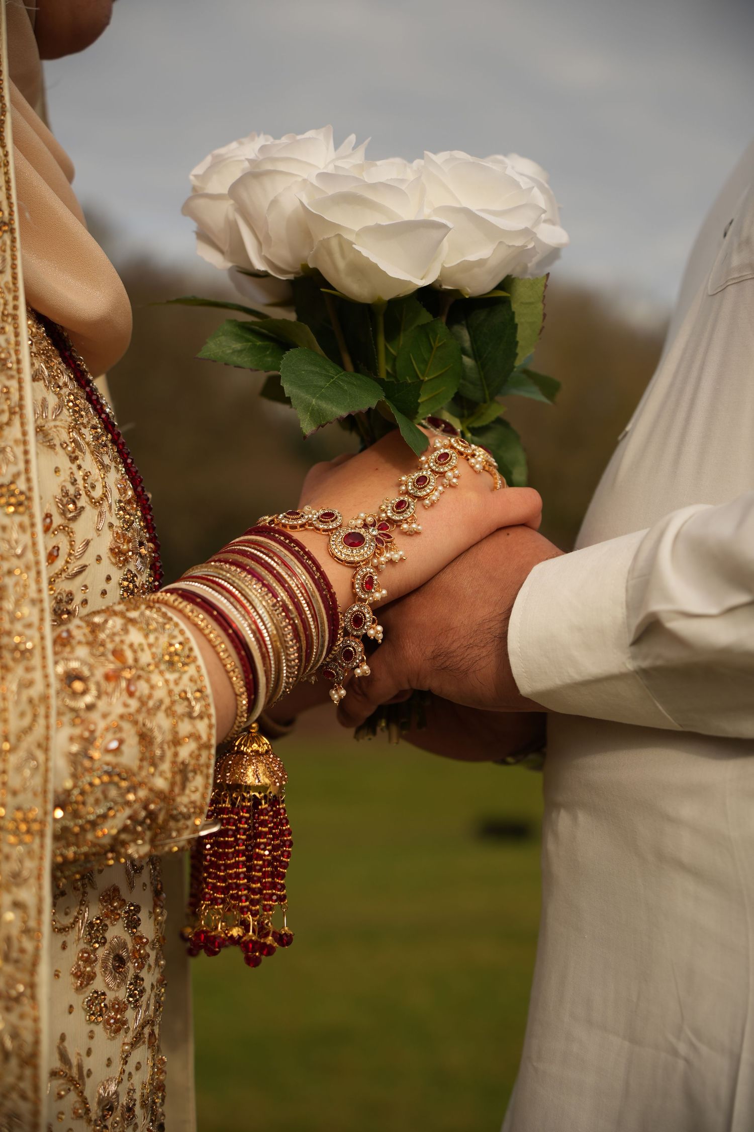 indian bride and groom hold bouquet of roses. Tied in Time Photography.