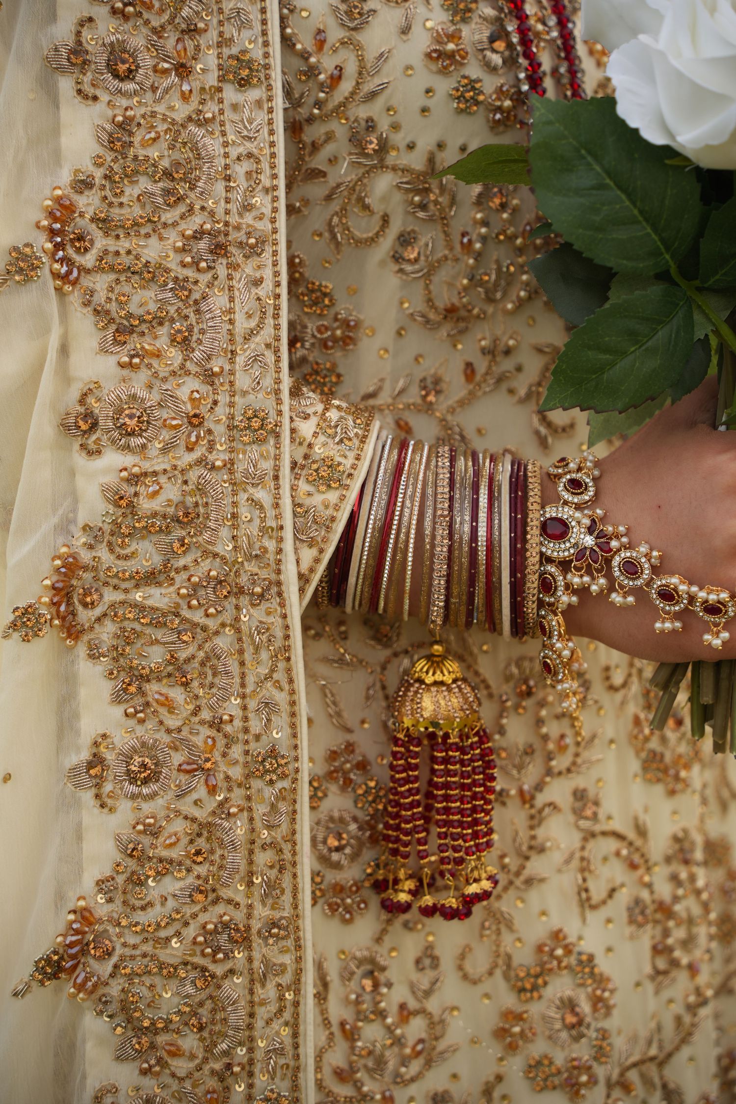 Indian bride holding white rose bouquet and red and gold bangles. Tied in Time Photography.