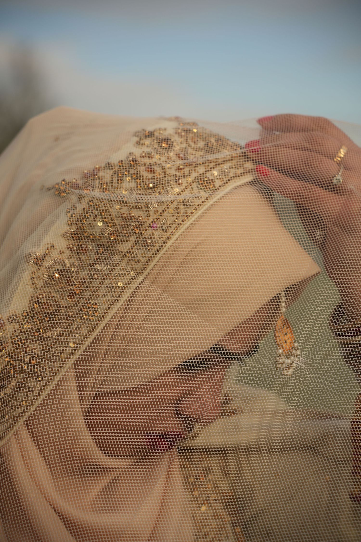 bride adjusting hijab under white veil. Tied in Time Photography.