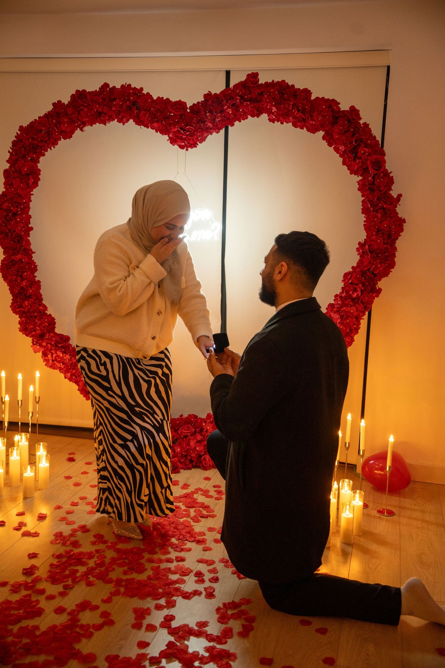 groom on one knee, proposing and looking up at bride. bride covering her mouth and laughing. Tied in Time Photography.