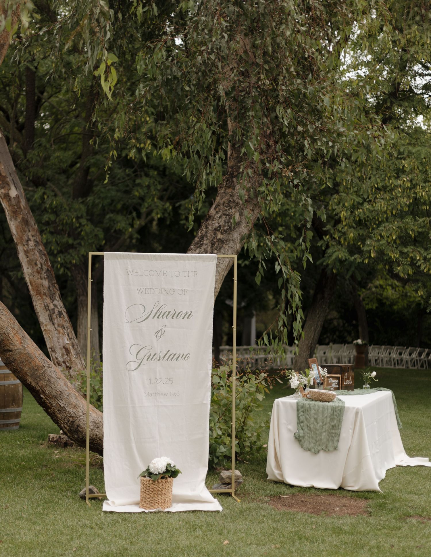White fabric wedding ceremony backdrop setup in garden with elegant signage.