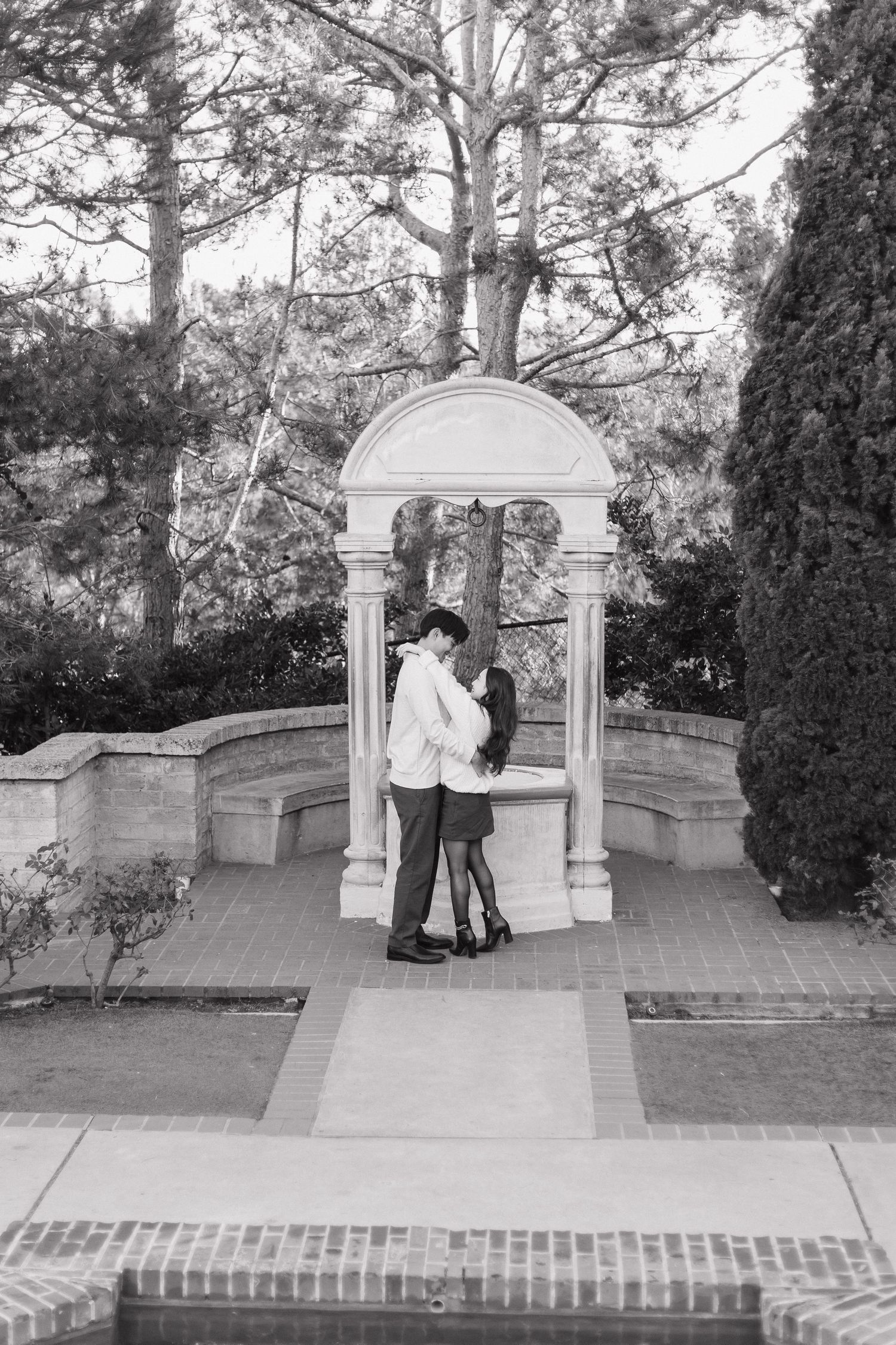 Black and white photo series of a couple by an ornate stone archway.