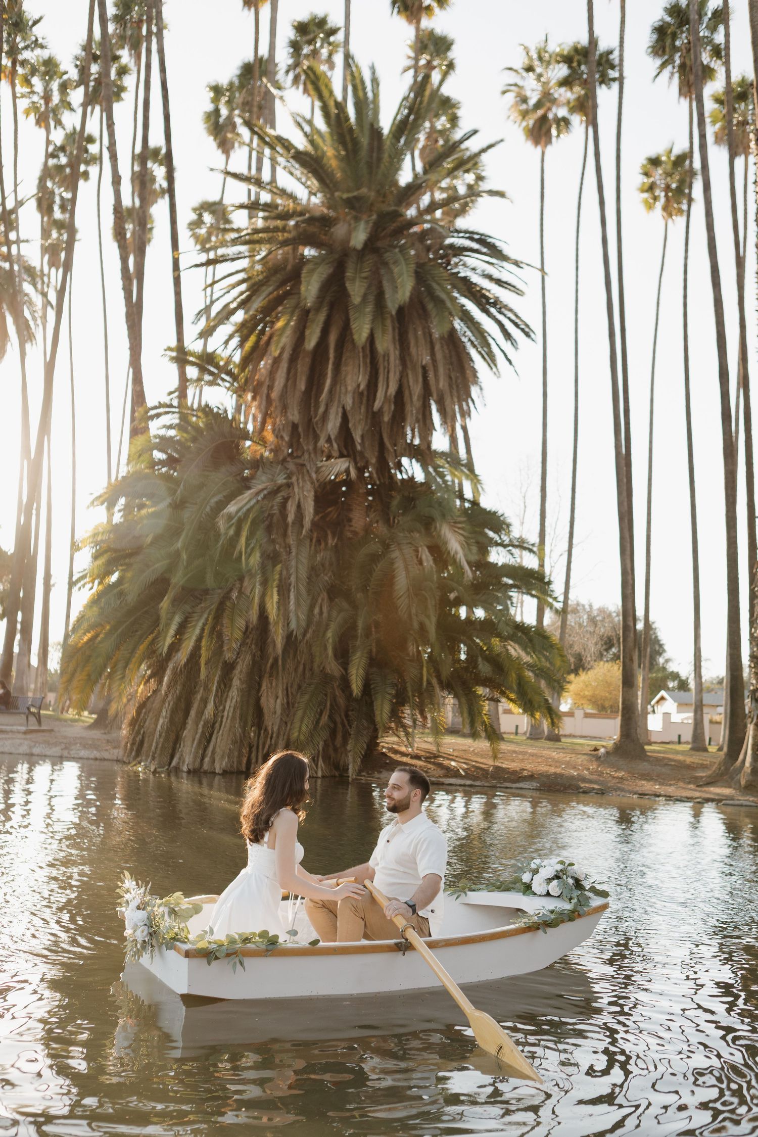 White rowboat floats among palm trees in a tranquil lagoon during golden hour.