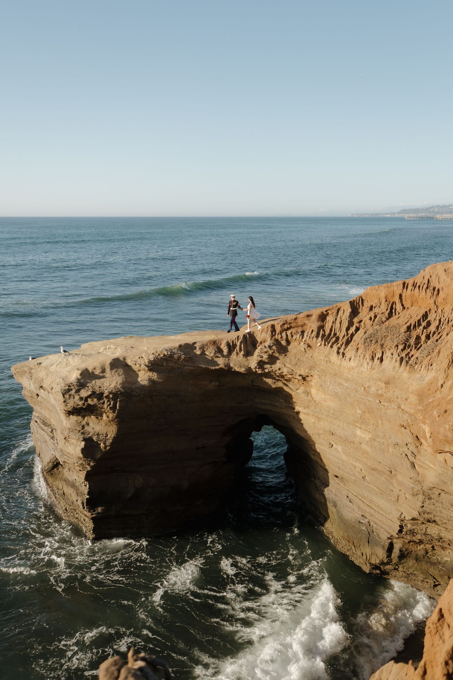 Natural stone arch formation over ocean waves with dramatic coastal scenery.